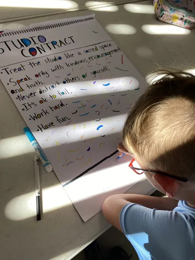 Young learner writing the studio contract in The Spark Studio